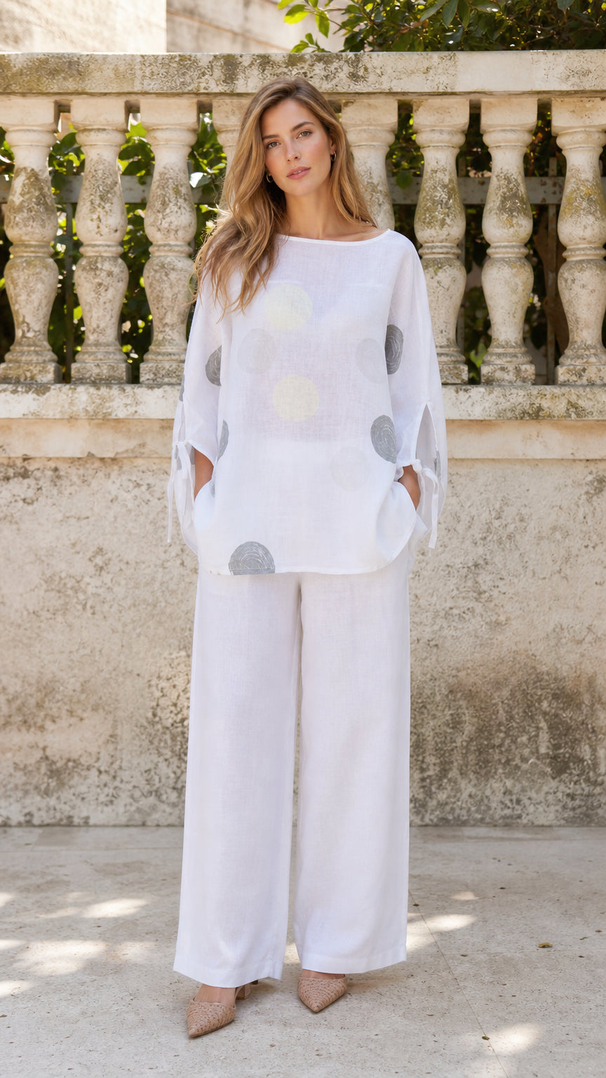 Front view of woman wearing white polka dot tunic and wide-leg pants set