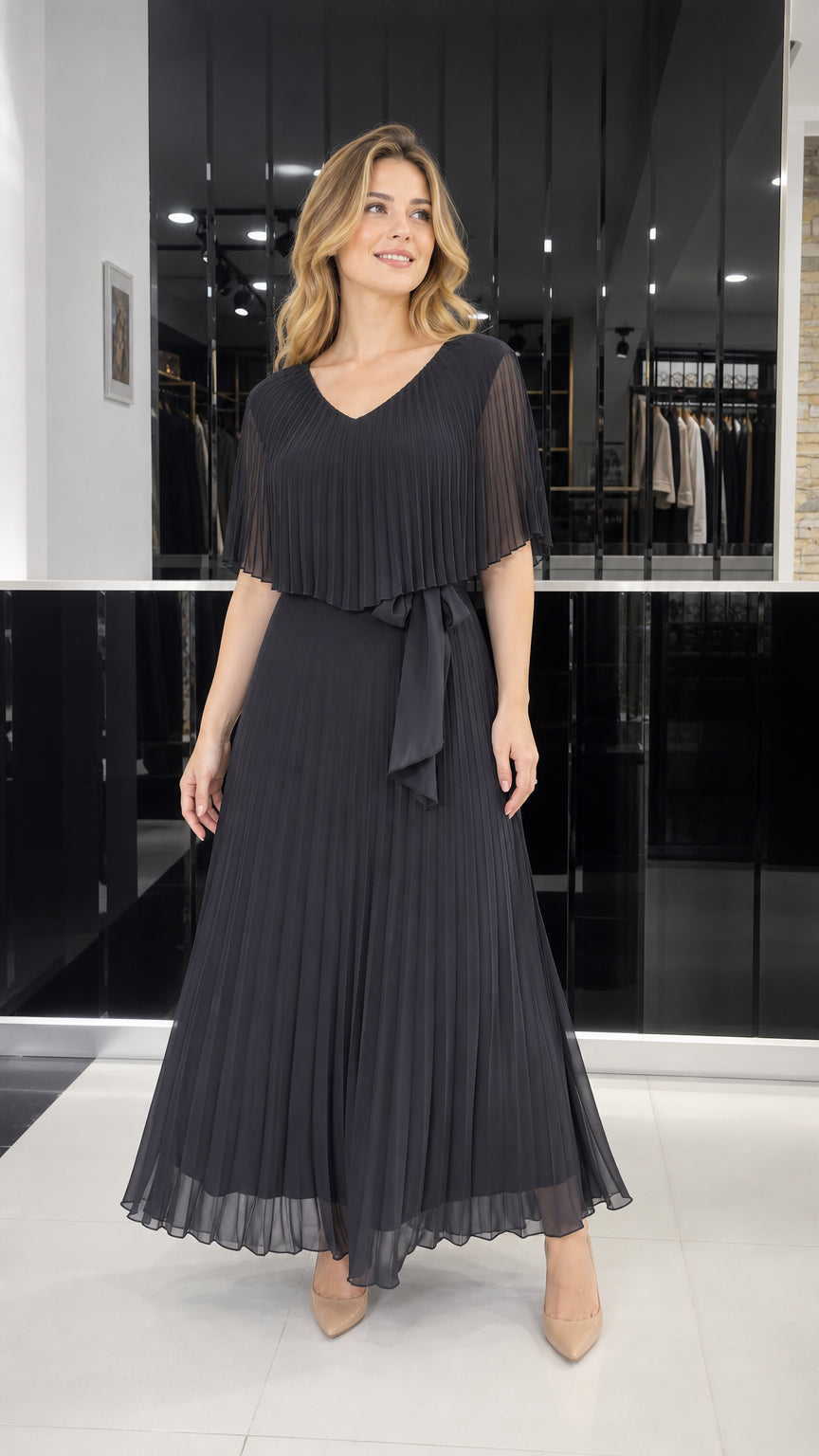 Model wearing black pleated cape overlay maxi dress, front view