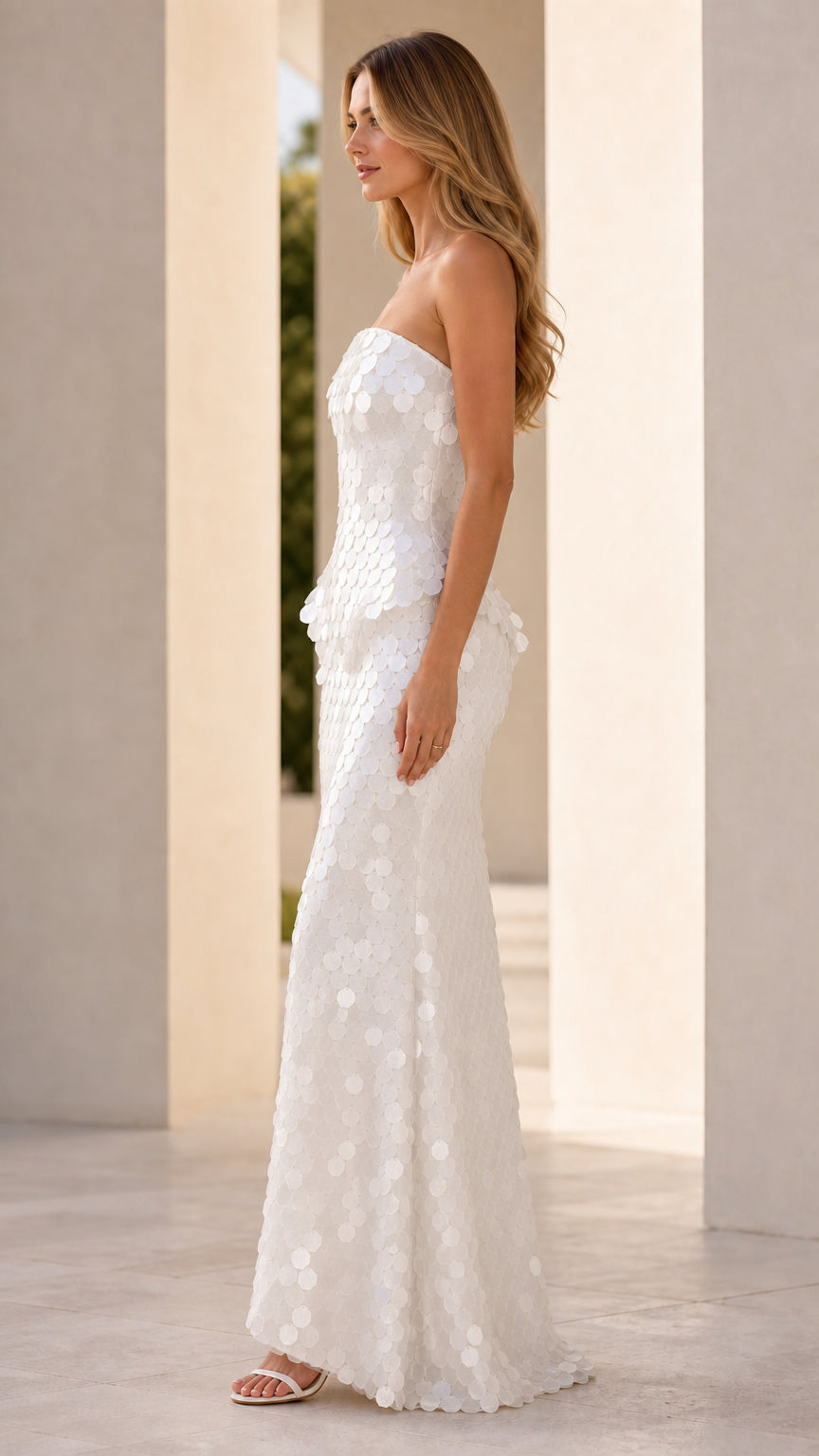 Side profile of model wearing white sequin strapless maxi dress