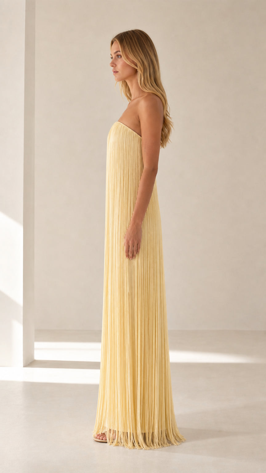 Side profile of model in yellow pleated maxi dress