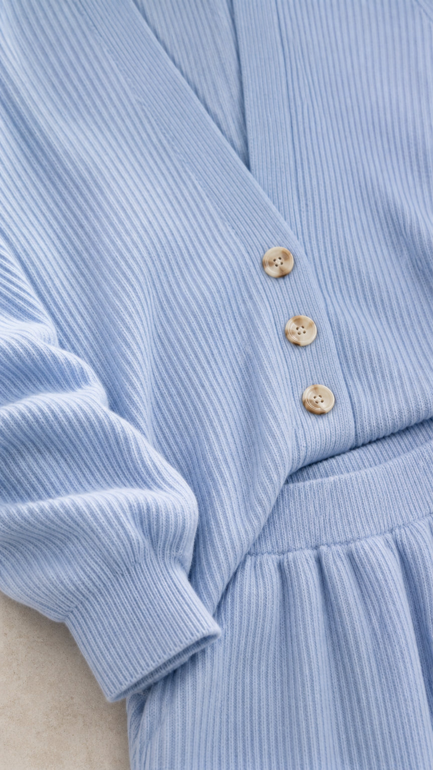 Close up of light blue cardigan buttons and ribbed knit texture