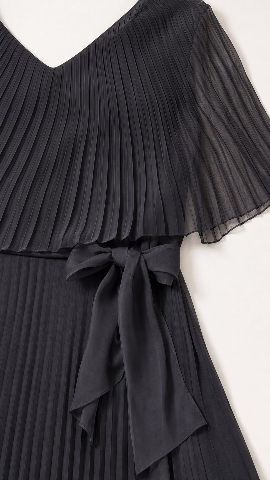 Close-up of black pleated fabric and waist tie detail