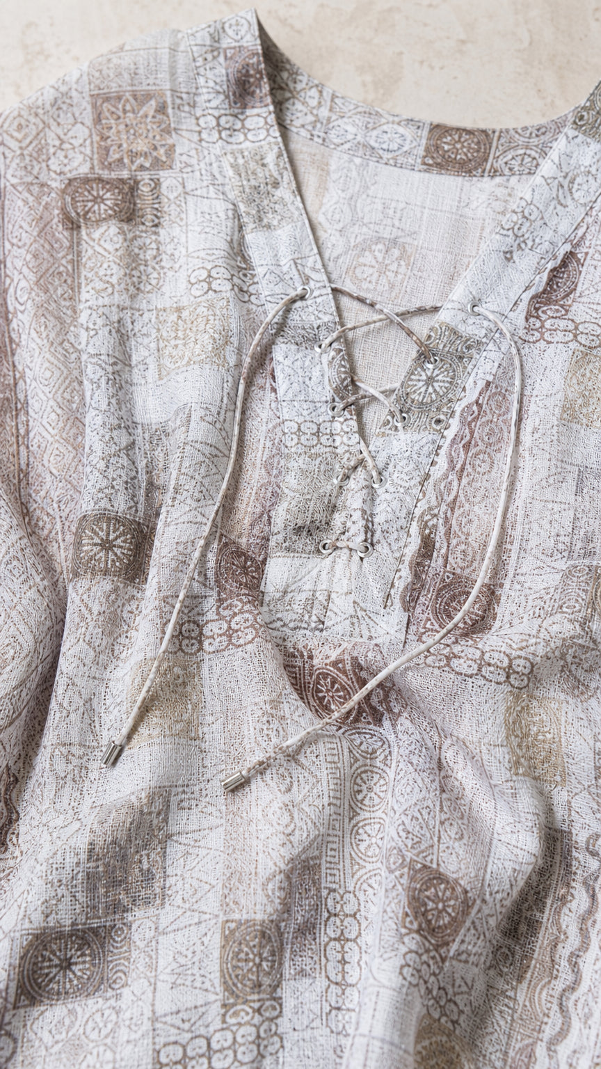 Close-up detail of lace-up neckline and printed fabric