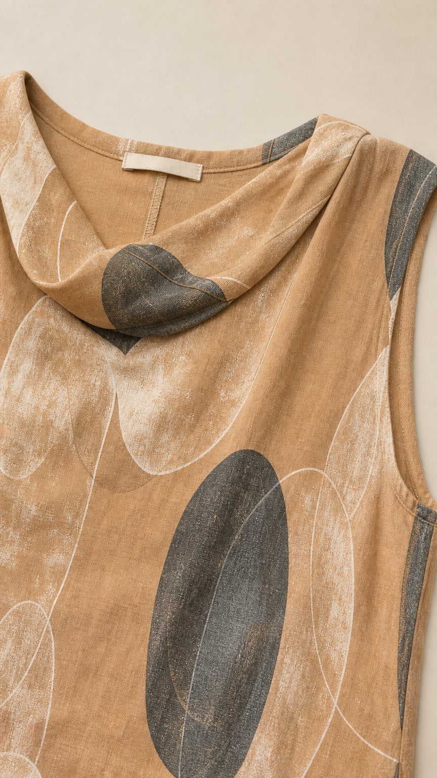 Close-up detail of cowl neckline and abstract pattern on camel top