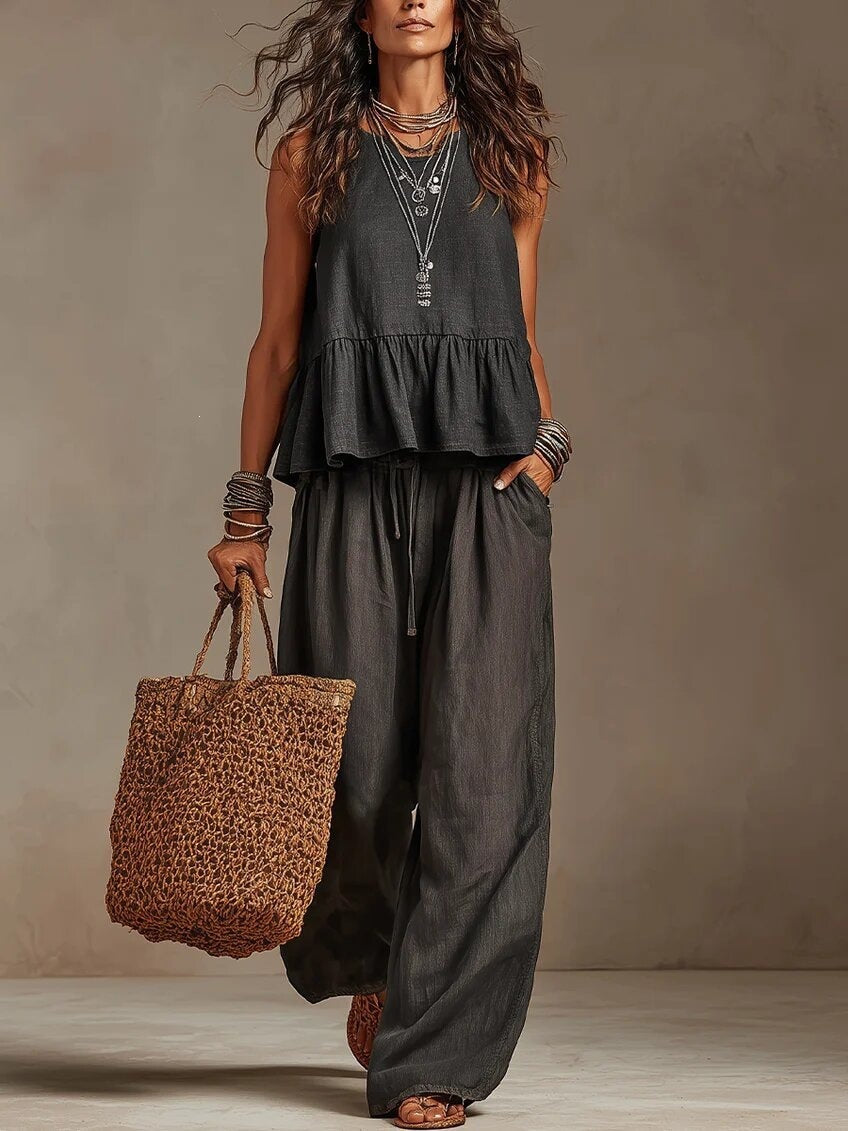 Woman wearing black boho sleeveless peplum top and wide leg pants set
