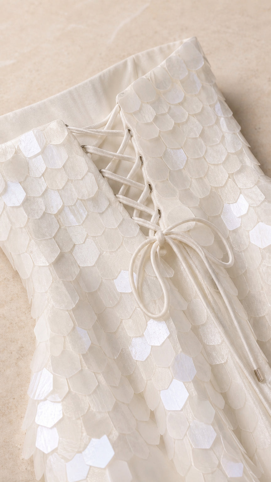 Close-up of fabric texture and lace-up back detail on white dress
