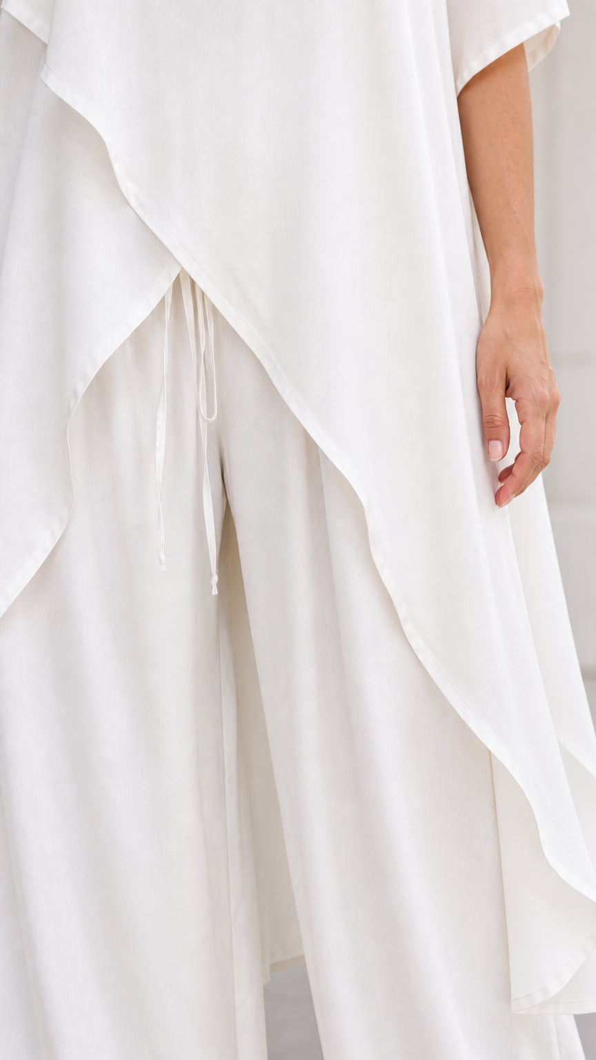 Close-up detail of white tunic layered hem and drawstring pants