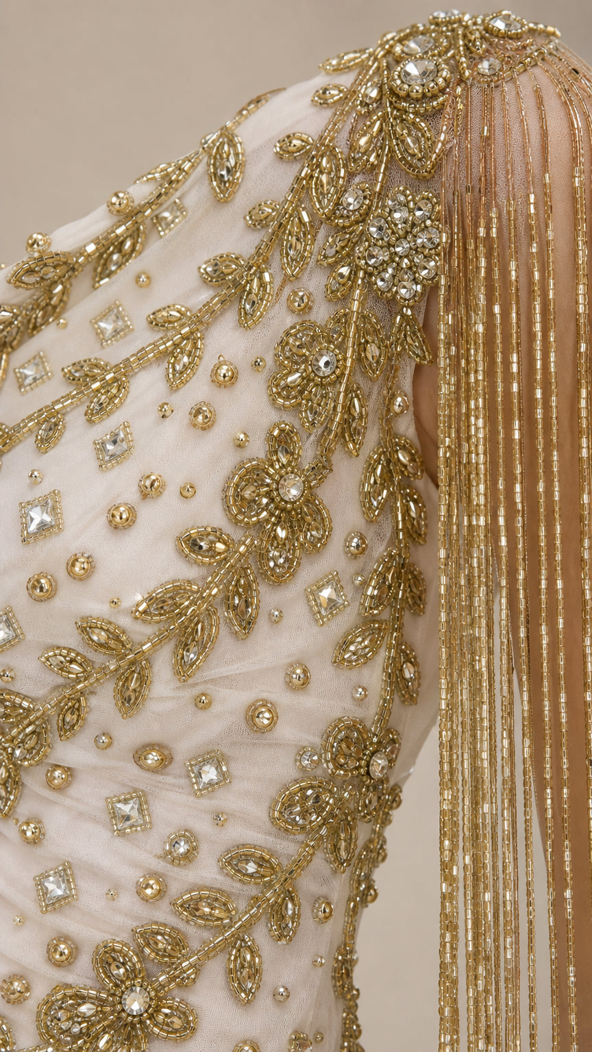 Close-up detail of gold embroidery and fringe on gown shoulder