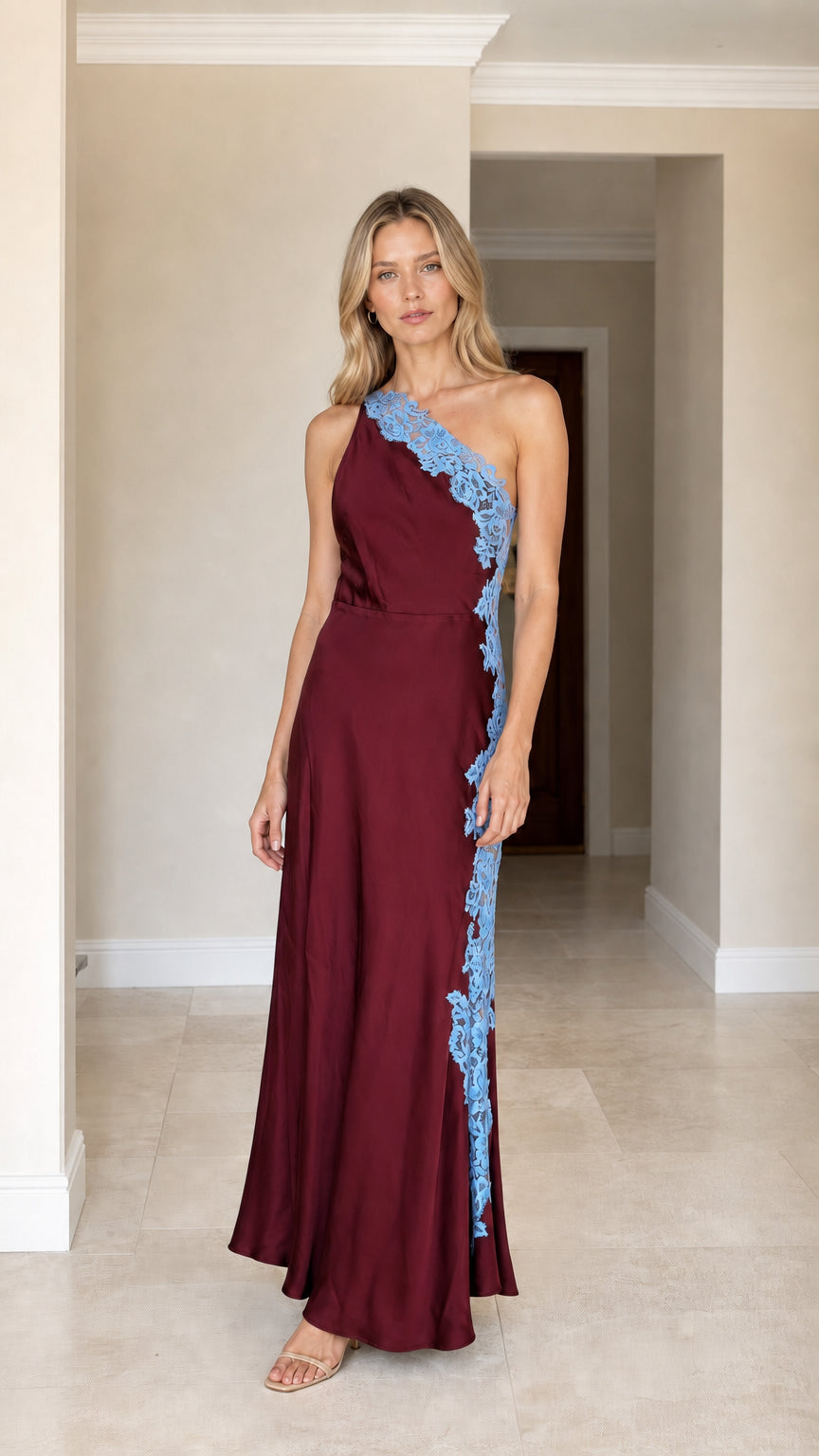 Front view of woman wearing burgundy one-shoulder satin maxi dress with blue lace applique