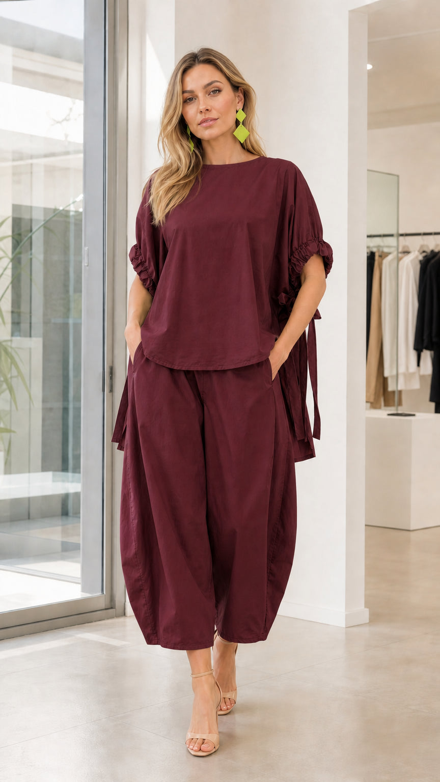 Model wearing burgundy two-piece lantern pants set